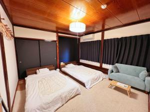 白川村白川乡家族旅馆的一间卧室配有两张床和一张蓝色椅子