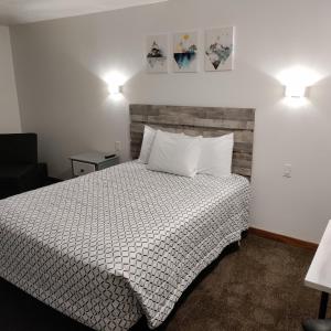 萨利纳High Desert Inn的一间卧室配有一张带白色床单和两盏灯的床。