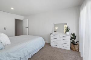 皮克顿Peaceful Escape - Picton Holiday Apartment的一间白色卧室,配有一张床和梳妆台上的电视
