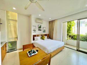 岘港Babylon Garden Da Nang的一间卧室配有一张床、一张桌子和一个窗户。