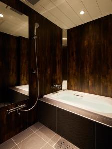 新泻HOTEL Us Racecourse Adult only的带浴缸的浴室,设有木墙