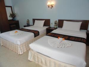 功孟海滩假日旅馆的配有白色床单的酒店客房内的两张床