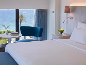 依克希亚Rhodes Bay Hotel & Spa的酒店客房配有白色的床和蓝色椅子