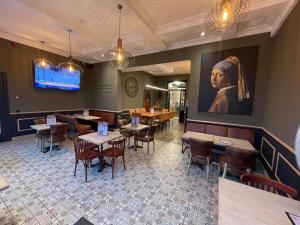 奥通Hôtel Maison Demelenne的餐厅设有桌椅,墙上挂有绘画作品