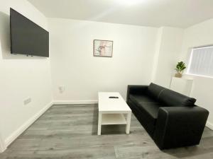 利兹Tong Apartments的客厅配有黑色沙发和白色桌子