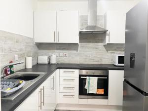 利兹Tong Apartments的白色的厨房设有水槽和炉灶。