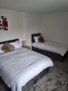 埃尔斯米尔港3 bedroom house-Ellesmere Port的一间卧室配有两张带白色床单的床