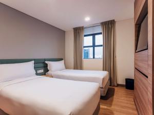 新加坡Novotel Living Singapore Orchard的酒店客房设有两张床和电视。