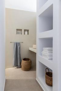 莫罗斯帕罗Citadela Paros Molos - Beachfront Maisonette with Plunge Pool的浴室设有白色的书架、毛巾和篮子