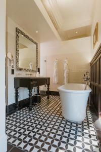 伦敦The LaLit London - Small Luxury Hotel of the World的带浴缸、水槽和镜子的浴室