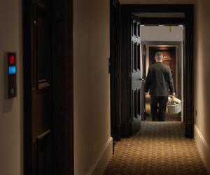 伦敦The LaLit London - Small Luxury Hotel of the World的一个人在走廊上用篮子走下