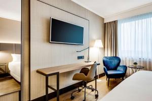 迭戈姆NH布鲁塞尔机场酒店的酒店的客房,设有书桌和墙上的电视