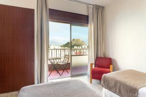 阿利坎特雷乌卡酒店的一间卧室配有一张床和一张红色椅子,并设有一个阳台