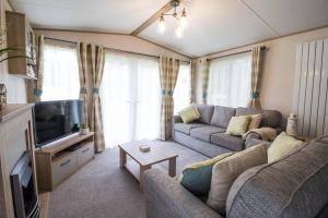 威利Lovely 6 Berth Caravan With Wi-fi At Weeley Bridge In Essex Ref 69015r的带沙发和电视的客厅