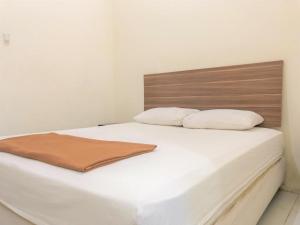 索龙Hotel Lido 88 Sorong Mitra RedDoorz的一张带木制床头板的白色床和两个枕头