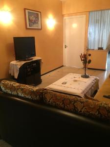 卡萨布兰卡Room in Guest room - Property located in a quiet area close to the train station and town的客厅配有桌子和电视机