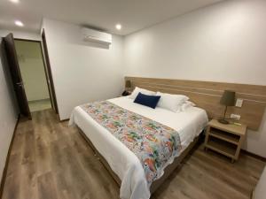 麦德林EcoHub Hotel Medellin的一间卧室配有一张大床和一张带台灯的桌子