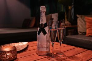 博克斯特尔Bed & Wellness Boxtel的一瓶香槟和一张桌子上的两杯酒