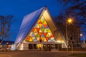 基督城Ramada Suites by Wyndham Christchurch City的一座晚上有彩色玻璃外墙的建筑