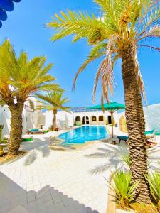 米多恩Maison Leila chambres d hotes的一个带游泳池和棕榈树的度假村