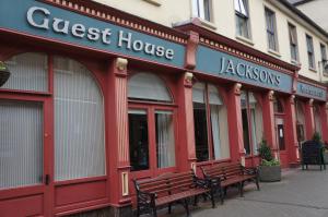 罗斯康芒Jacksons Restaurant and Accommodation的商店前有长凳的红色建筑