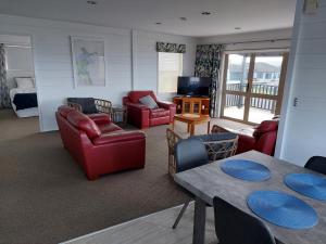 怀蒂昂格Whitianga Sea Views的一间带红色家具的客厅和一间卧室