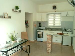蓬塔卡纳Dominican Dream Apartments的厨房配有白色橱柜、桌子和用餐室。