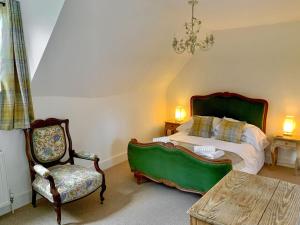 HollingbourneMoorhen Cottage的一间卧室配有一张床、一把椅子和一张桌子