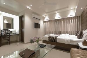 孟买Hotel Ariana Residency的一间卧室配有一张床、一张桌子和一张沙发