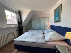 韦斯特兰Meer-Lust-Sylt sea cottage的一间卧室配有一张带蓝色床头板的床和窗户