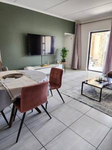 米德兰Loadshedding Equipped 2-Bed Apartment in Waterfall, Waterfall City的客厅配有桌椅和电视。