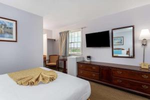 西丹尼斯科德角区旅程住宿的酒店客房设有一张床和一个带电视的梳妆台