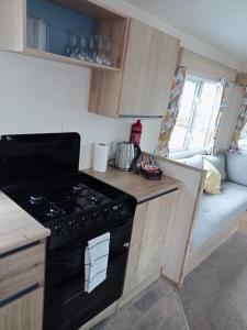 Lytchett MinsterNew 2 bed holiday home with decking in Rockley Park Dorset near the sea的一间带炉灶的厨房和一张沙发