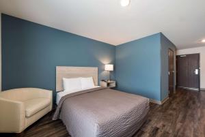 格林斯伯勒WoodSpring Suites Greensboro - High Point North的蓝色卧室,配有床和椅子