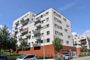 布拉格Apartment Hurka - 15 min do centra, garaz的一座白色的公寓楼,前面设有停车场