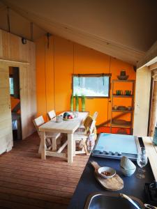 兰波雷基奥巴克里尔露营旅馆的一间设有桌子的客房和一间带橙色墙壁的厨房