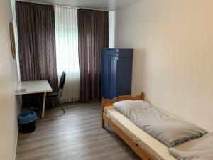 丁斯拉肯City Hotel Dinslaken的一间卧室配有一张床、一张书桌和一个窗户。