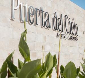 巴卡拉尔Puerta del Cielo Hotel Origen的前面有植物的医院的标志