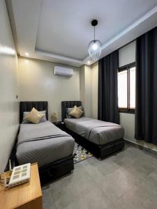马拉喀什Moderne, lumineux & spacieux avec balcon -Central -Wifi-Smart TV-Clim的一间卧室设有两张床、一张桌子和窗户。