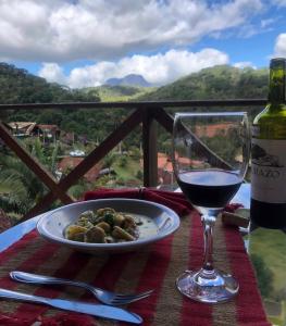 多明戈斯马丁斯Chalé Vista Azul的一张桌子,上面放着一盘食物和一杯葡萄酒