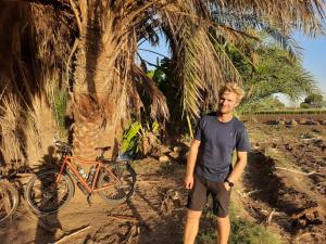明亚Village Room in the Countryside的站在自行车旁的棕榈树旁的男人