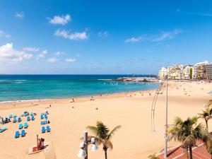 大加那利岛拉斯帕尔马斯Precioso apartamento a 150 metros de la Playa的海滩上,有椅子和棕榈树,还有大海