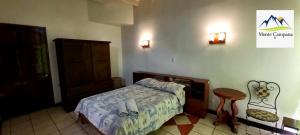 BirríHotel Monte Campana Heredia的卧室配有1张床、1张桌子和1把椅子