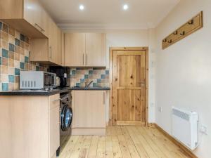 EdzellSmiddy Bothy的厨房配有木制橱柜、洗衣机和烘干机