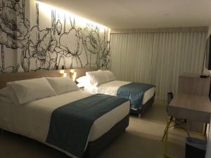 梅尔加Hotel Karmel的酒店客房设有两张床,墙上挂有壁画