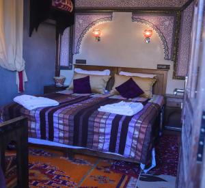 伊姆利尔Riad Atlas Panorama的一间卧室配有一张铺有紫色和白色床单的床