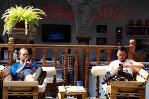 库斯科Pariwana Hostel Cusco的坐在椅子上的两个人看着手机