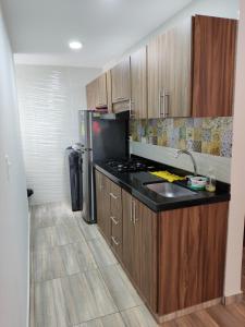 圣希尔Hermoso y Cómodo Apartamento--Excelente Ubicación的厨房配有木制橱柜和黑色台面
