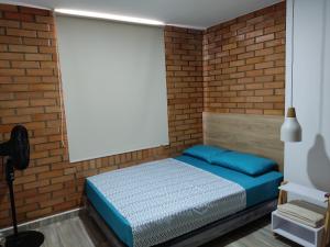 圣希尔Hermoso y Cómodo Apartamento--Excelente Ubicación的一间卧室设有砖墙和一张床