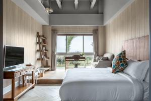 鹅銮鼻垦丁姊妹沙滩别墅 的一间卧室配有一张床、一台电视和一张沙发